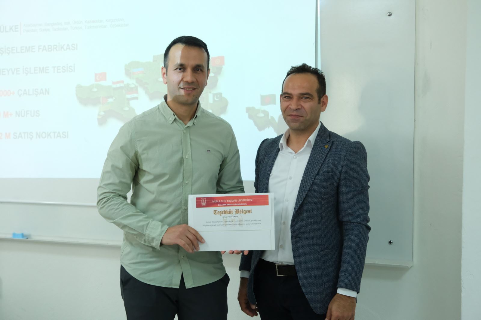 Following the talk, during the presentation of certificates of appreciation, two participants are posing for the camera whilst holding the certificate together.